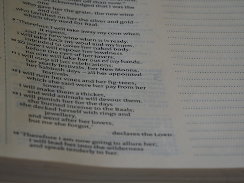 The image shows a close-up of a Bible page with text primarily from the book of Hosea. The page is slightly tilted, and the lighting creates shadows on the paper, emphasizing the printed words.