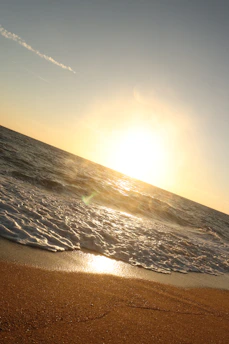 Sunset over the calm Black Sea with gentle waves touching the sandy shore near Sunny Beach.