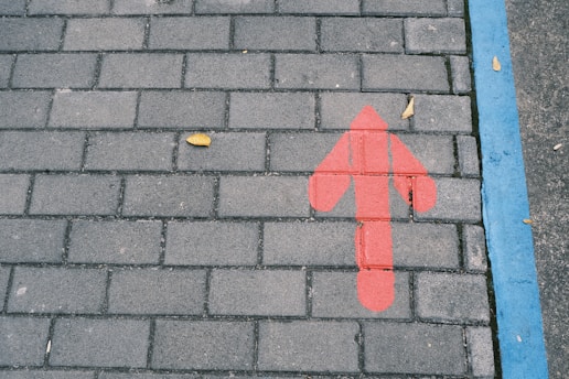 a red arrow painted on a brick sidewalk