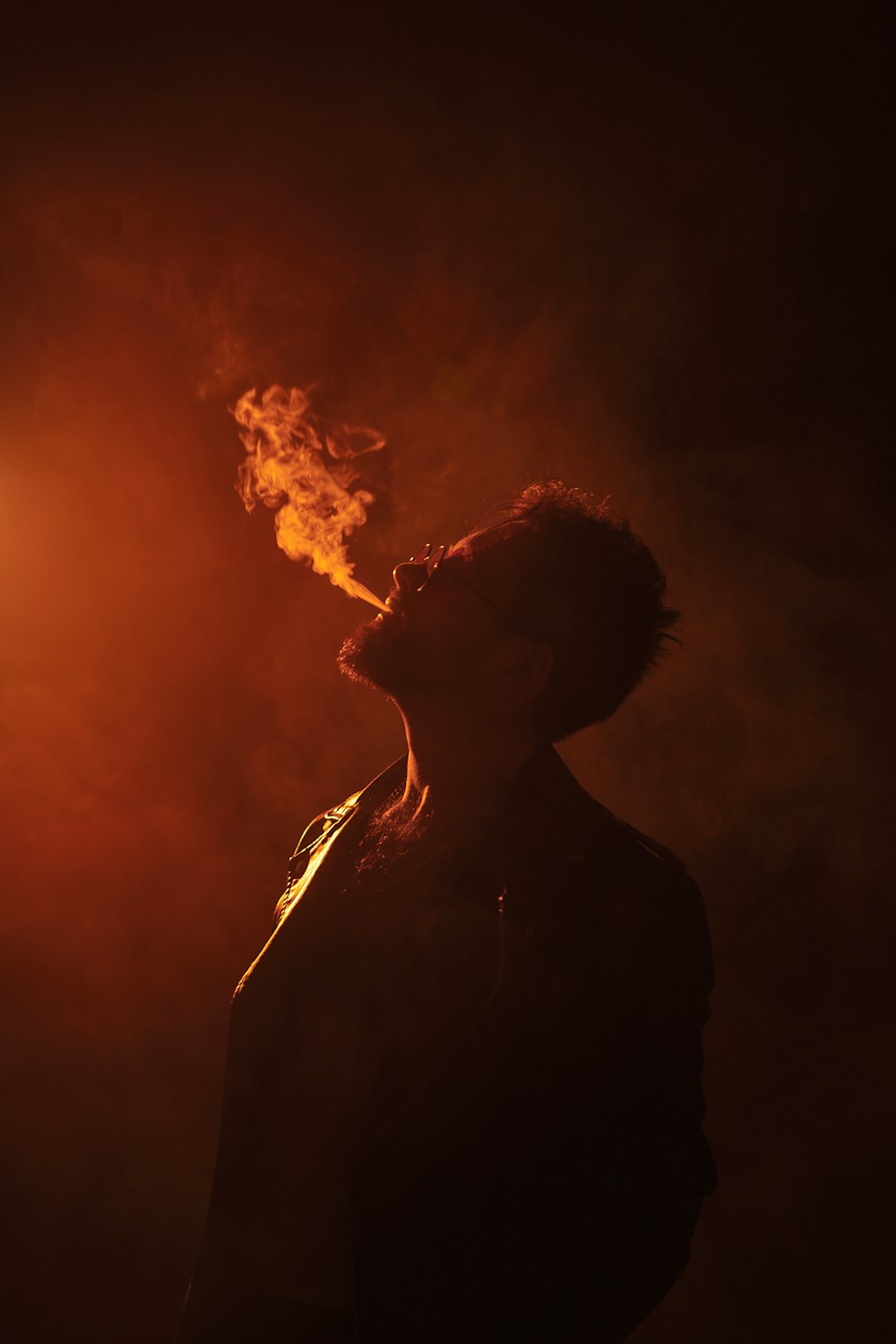 a man standing in the dark with a cigarette in his mouth