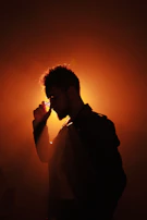 Natural light silhouette of a man running fingers through a thick beard, emphasizing texture.