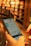 A person is holding a smartphone in their hands, navigating an online library or e-book application with blurred bookshelves in the background, giving a sense of depth and focus on the technology.