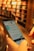 A person is holding a smartphone in their hands, navigating an online library or e-book application with blurred bookshelves in the background, giving a sense of depth and focus on the technology.