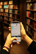 Library user scanning a book with a mobile phone at the checkout area