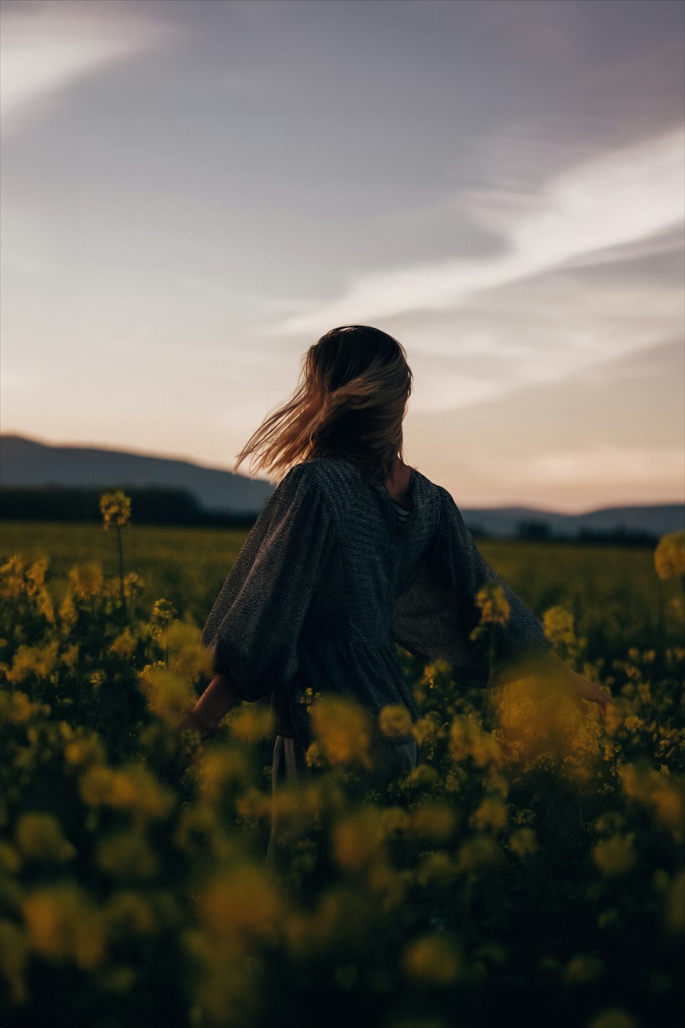 a woman standing in a field of yellow flowers