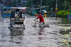 a man riding a bike through a flooded street