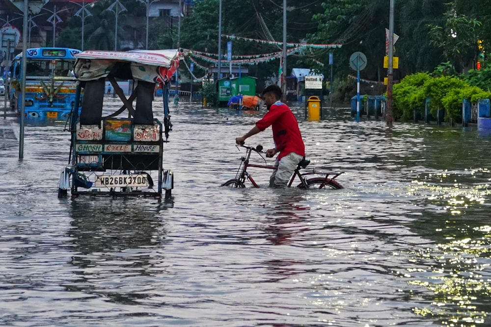 a man riding a bike through a flooded street
