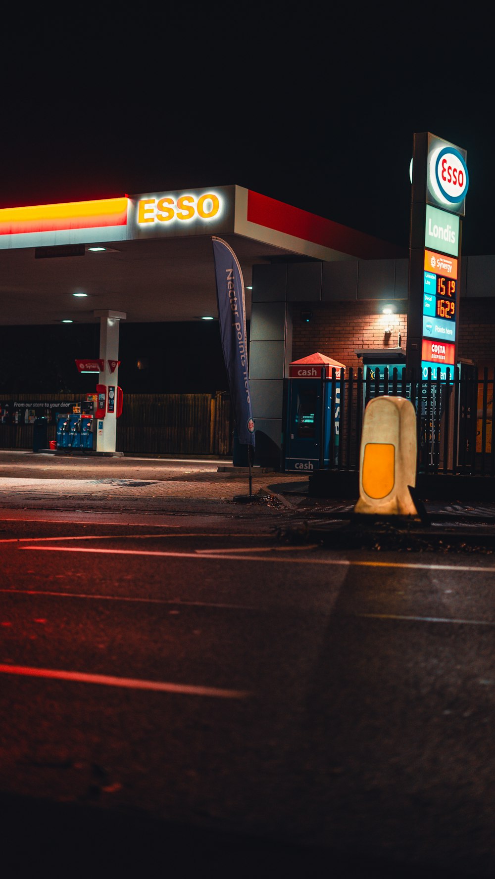 a gas station at night with a lit up sign