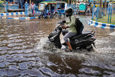 a man riding a motorcycle through a flooded street