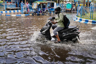 a man riding a motorcycle through a flooded street