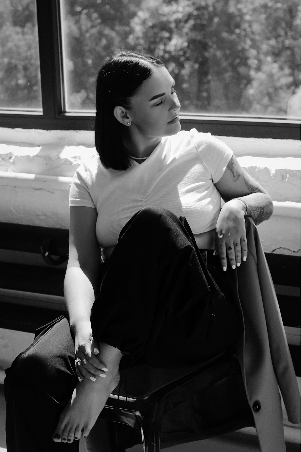 a black and white photo of a woman sitting on a bench