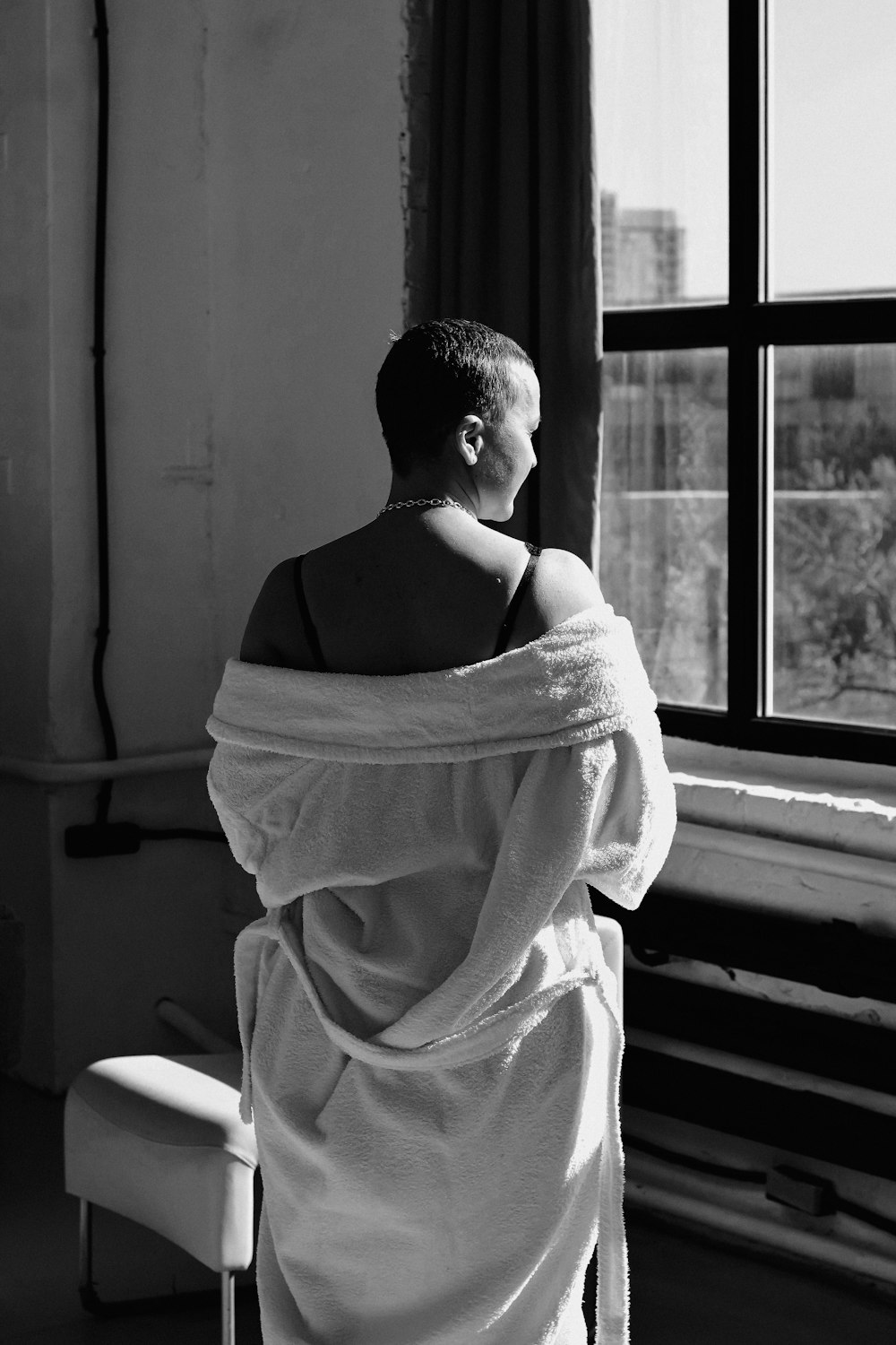 a man wrapped in a towel looking out a window