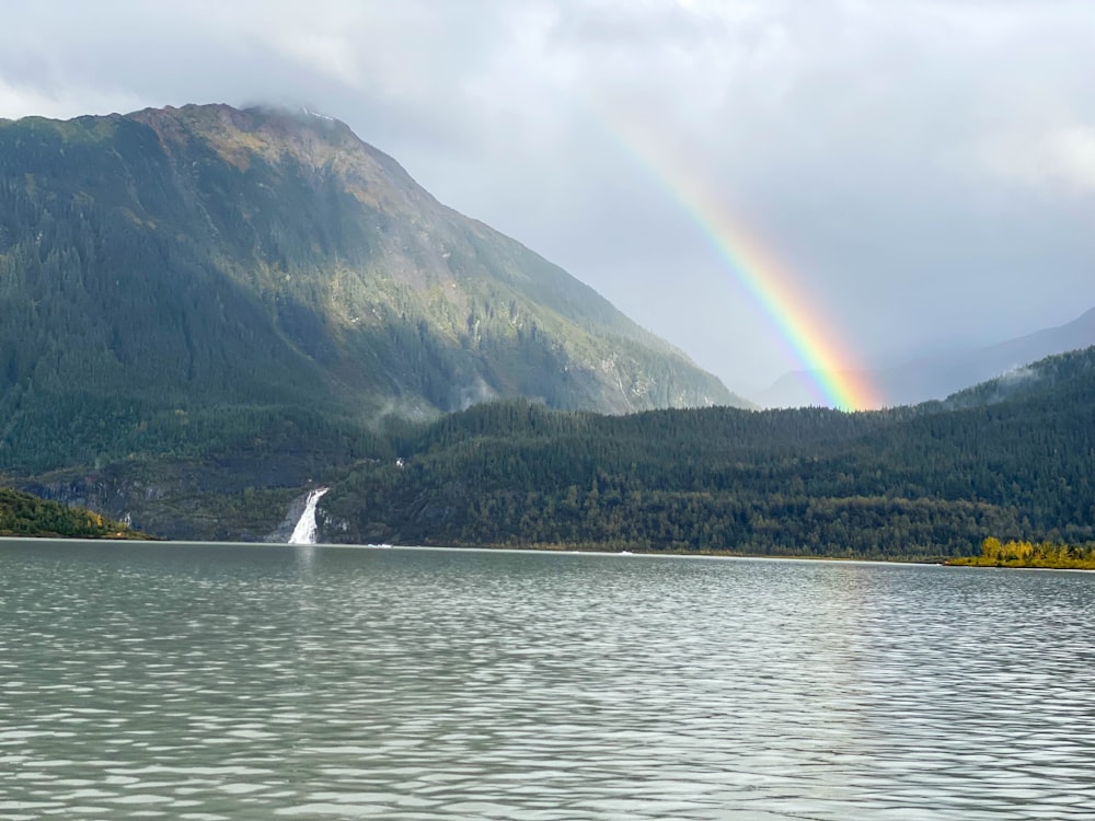 a rainbow in the sky over a mountain lake