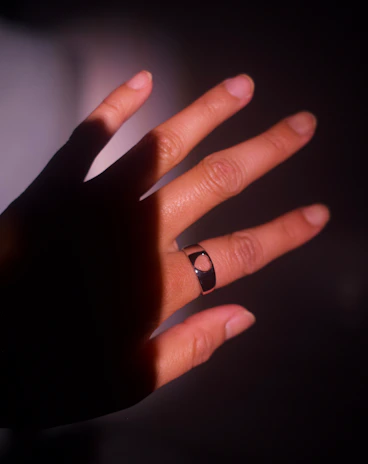 A stylish smart ring glowing subtly on a hand against a dark background