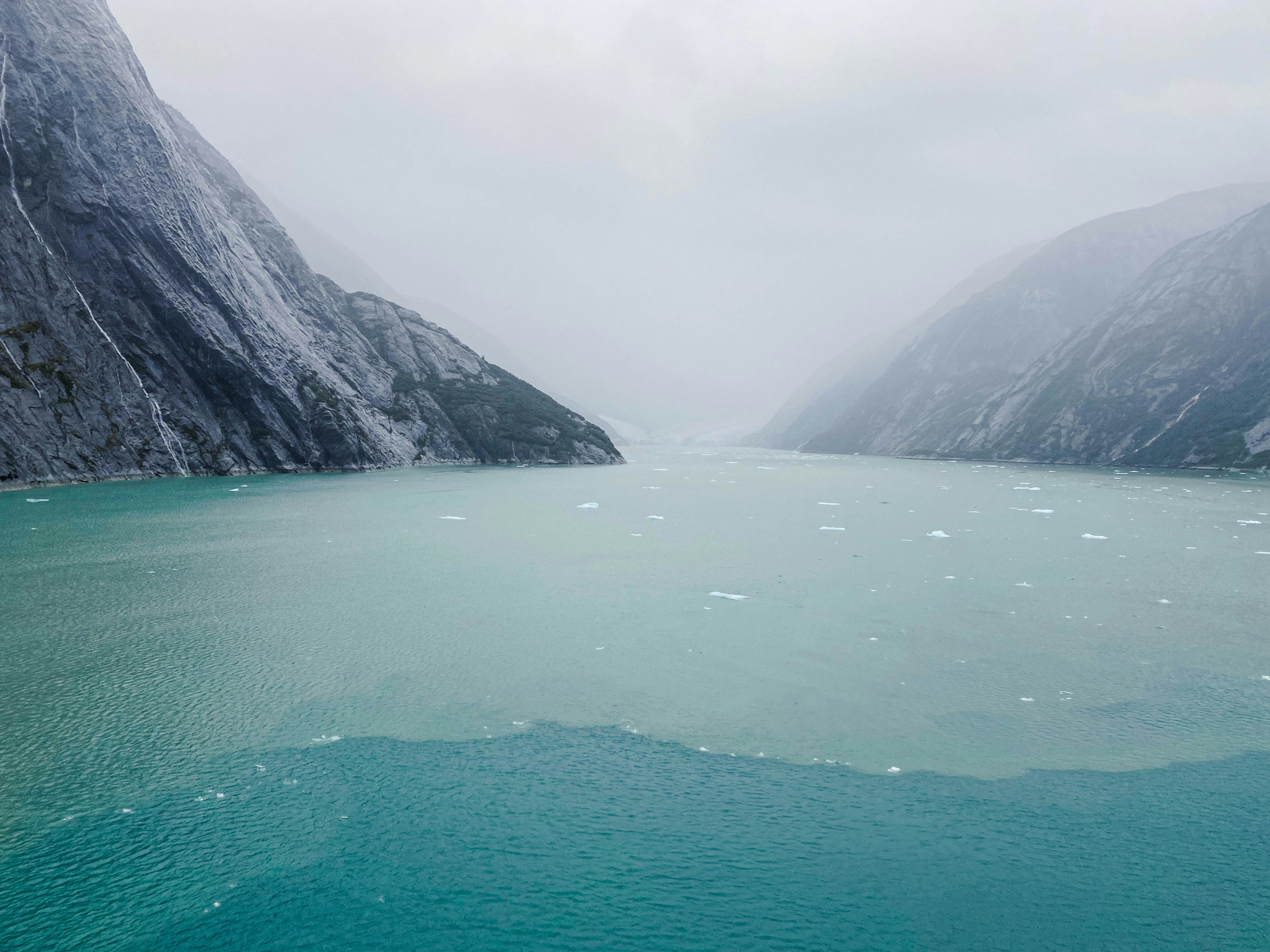 a large body of water surrounded by mountains, Glacier through the fog