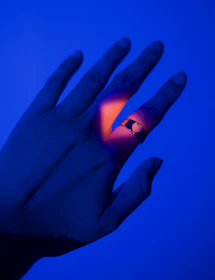 Close-up of a hand wearing the sleek Orukka Word ring glowing softly.