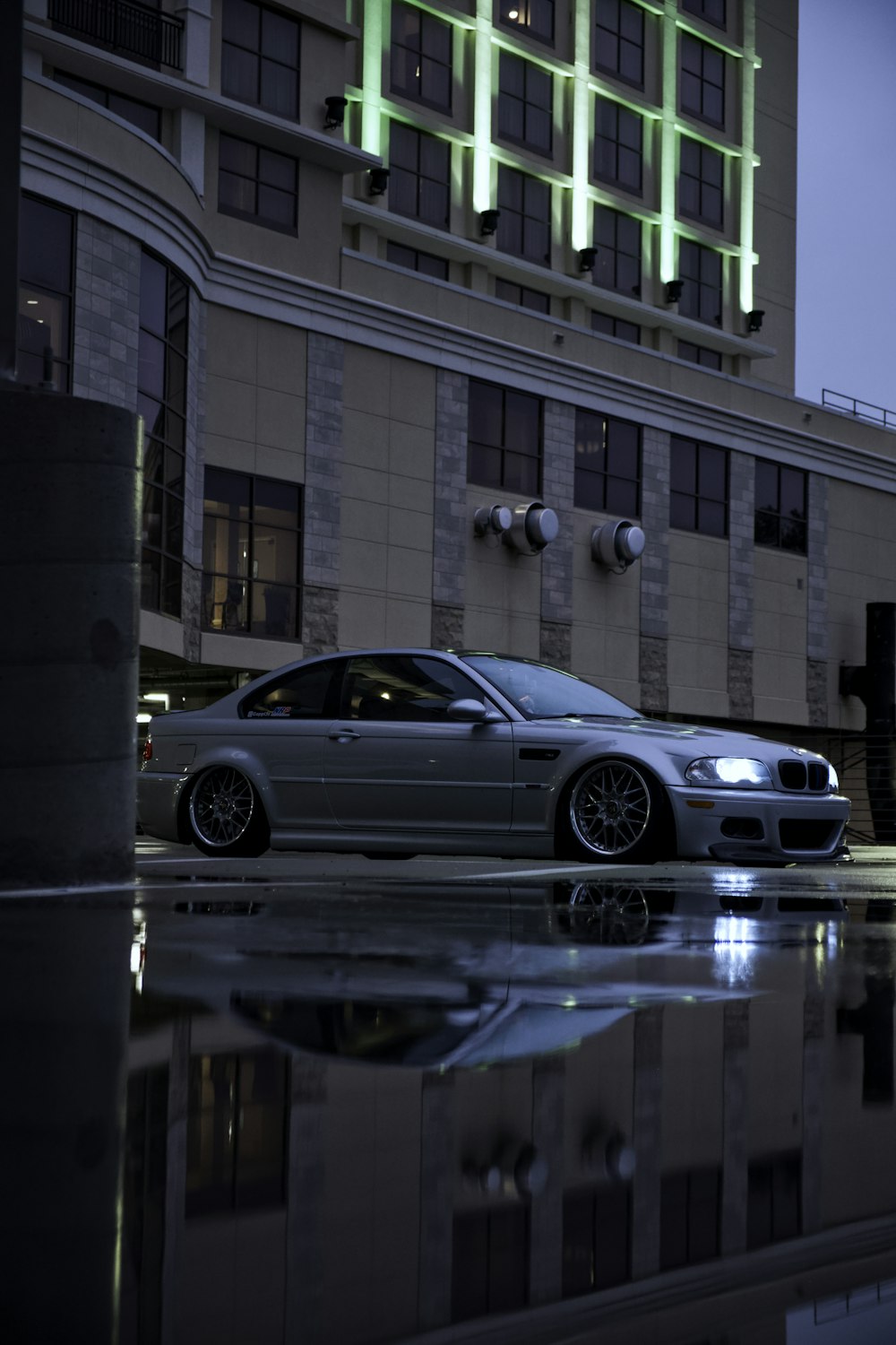 a silver car parked in front of a tall building