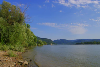 A serene riverside view of Portet-sur-Garonne with lush greenery and calm water.