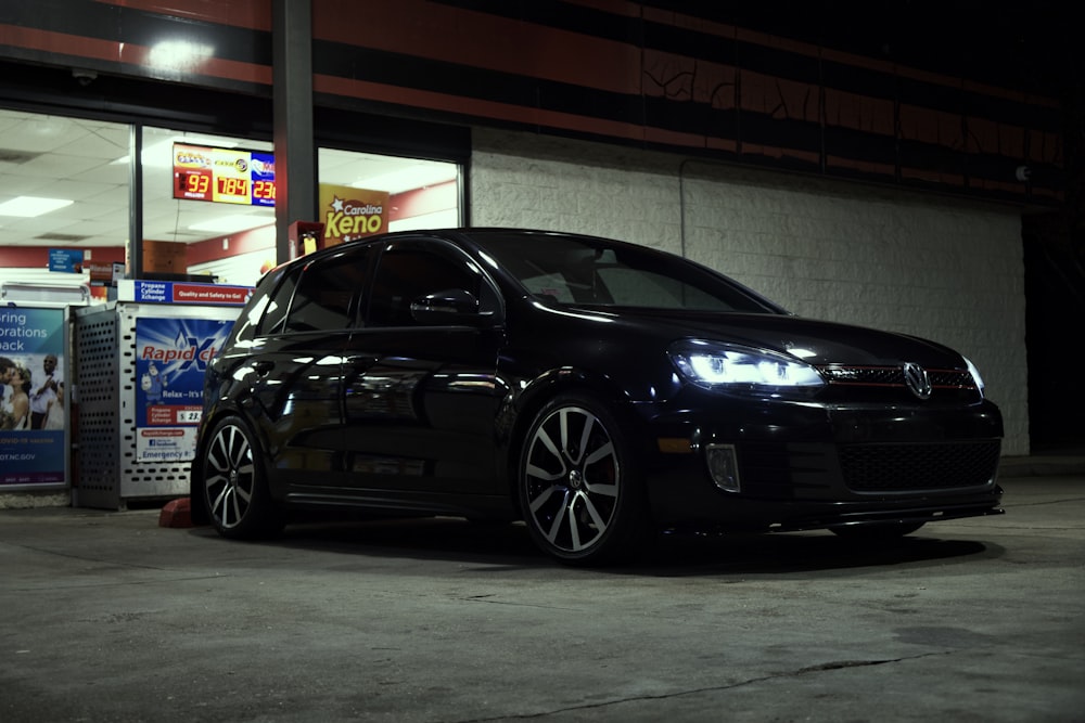 a black car parked in front of a gas station