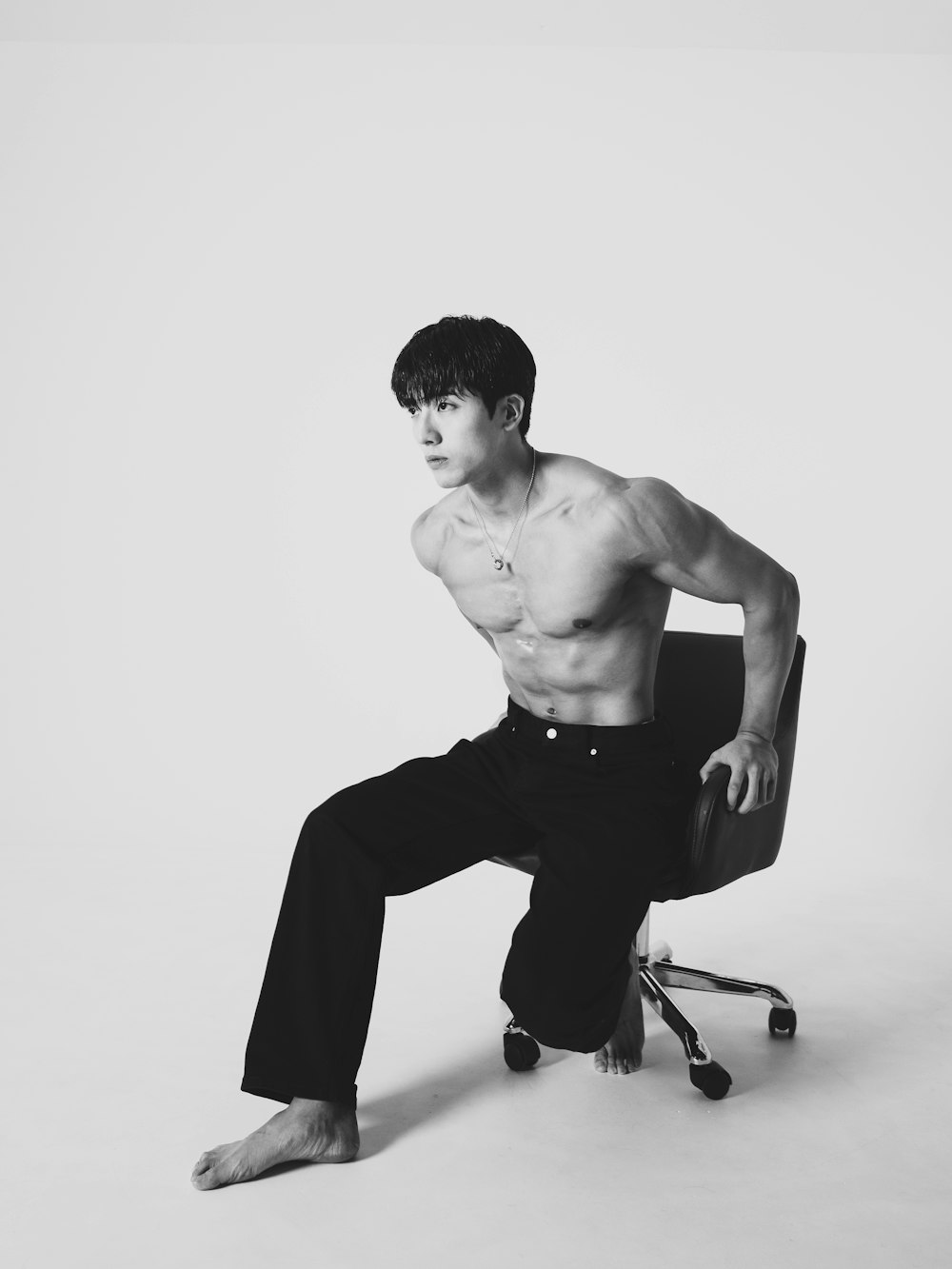 a shirtless man sitting in an office chair