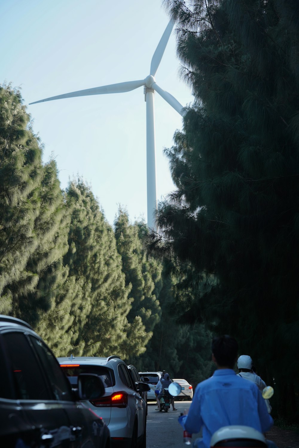 Un uomo in sella a una bicicletta lungo una strada accanto a una turbina eolica