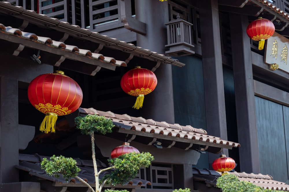 three red lanterns hanging from the side of a building