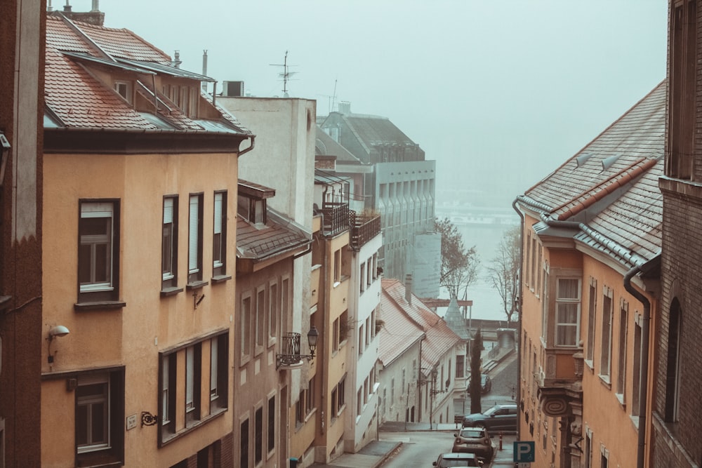 a city street with buildings and cars on a foggy day