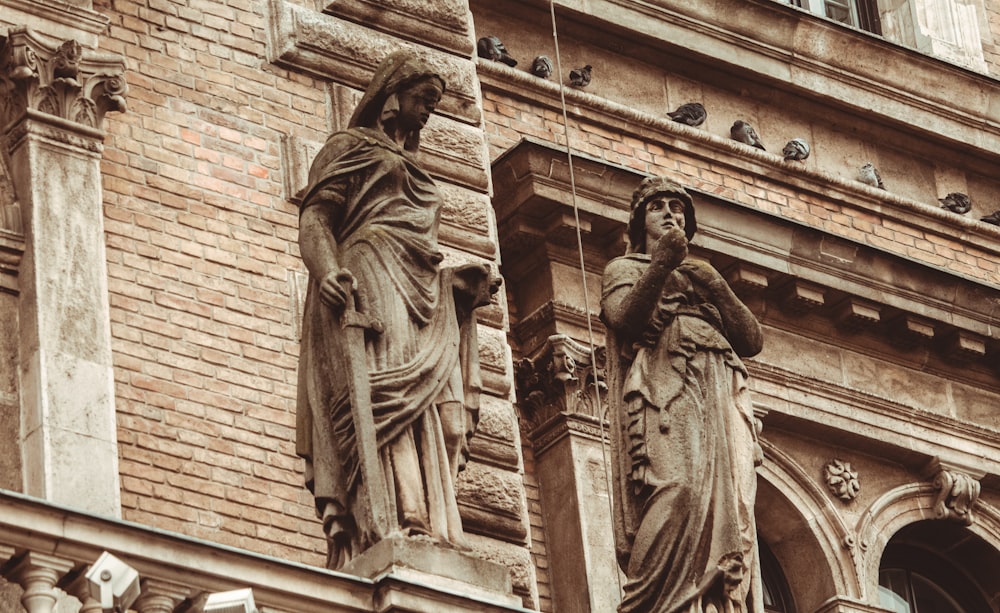two statues of women on the side of a building
