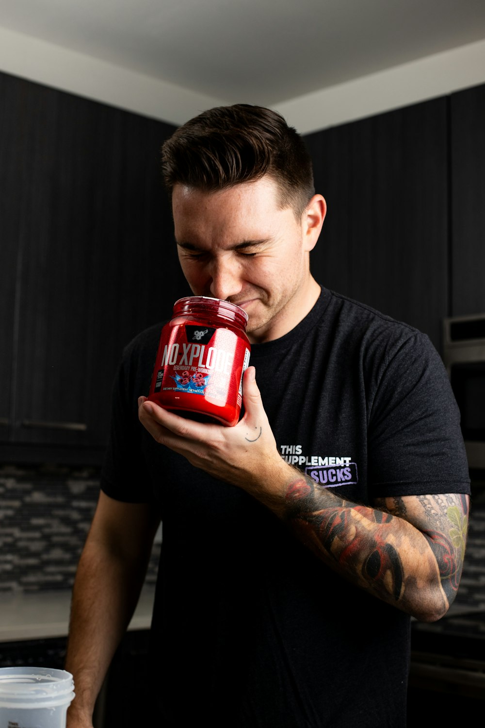 a man in a black shirt is holding a red jar