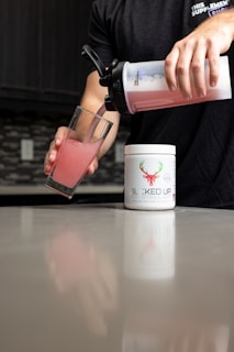 a person pouring a drink into a glass