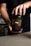 A person holding a black container labeled 'Super Human Pre-Workout' by Alpha Lion. The label has yellow and red text, indicating that it is a dietary supplement with a 'Lion's Blood Red Gummy Bear' flavor. The person's hands are visible, and they are wearing a dark shirt.