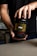 A person holding a black container labeled 'Super Human Pre-Workout' by Alpha Lion. The label has yellow and red text, indicating that it is a dietary supplement with a 'Lion's Blood Red Gummy Bear' flavor. The person's hands are visible, and they are wearing a dark shirt.