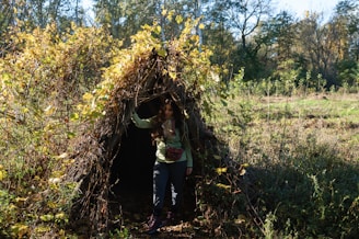 a woman standing in front of a teepee in the woods