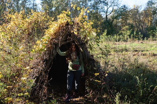 a woman standing in front of a teepee in the woods