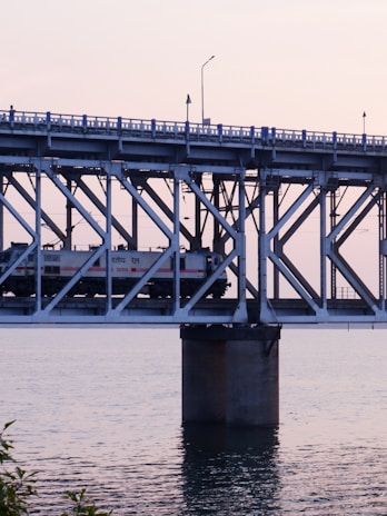 A train crossing a historic bridge at sunset.