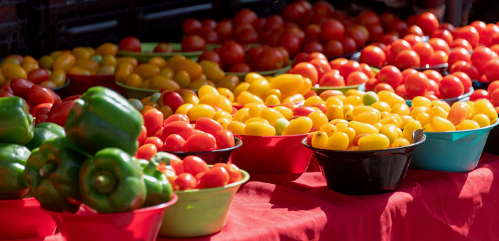 A vibrant bowl of fresh colorful vegetables and fruits arranged artistically on a wooden table.