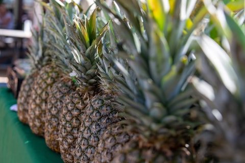 a row of pineapples sitting on top of a green table