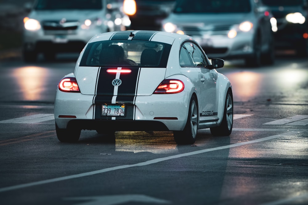 a white car driving down a street at night