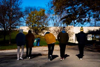 A group of friends wearing different styles of wool hats while walking through a park in autumn.