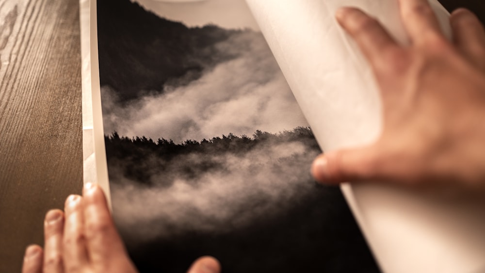 a person holding a book open to a picture of a mountain