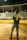 A baseball player stands on a field, holding a bat. The player is wearing a green jersey with the name 'CASTAÑEDA' and number '8' on the back. The field is lined with a yellow barrier, and there are empty bleachers in the background under a partially covered roof. The scene appears to be at night, with artificial lighting illuminating the area.