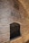 A textured brick wall with a large recessed area filled with stacked wine bottles. Above the recess, a sign reads 'Vina Belje,' accompanied by an emblem or logo, possibly depicting a building and the year 1697.