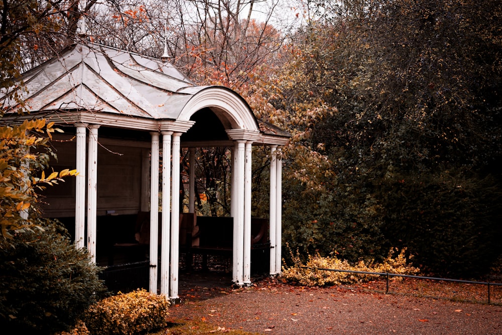 a white gazebo surrounded by trees in a park