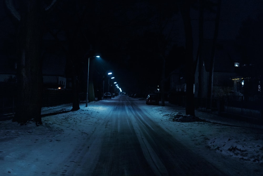 a dark street at night with snow on the ground