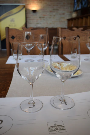 A close-up of clinking wine glasses during a Tuesday tasting event, warm lighting highlighting the rich reds and whites.
