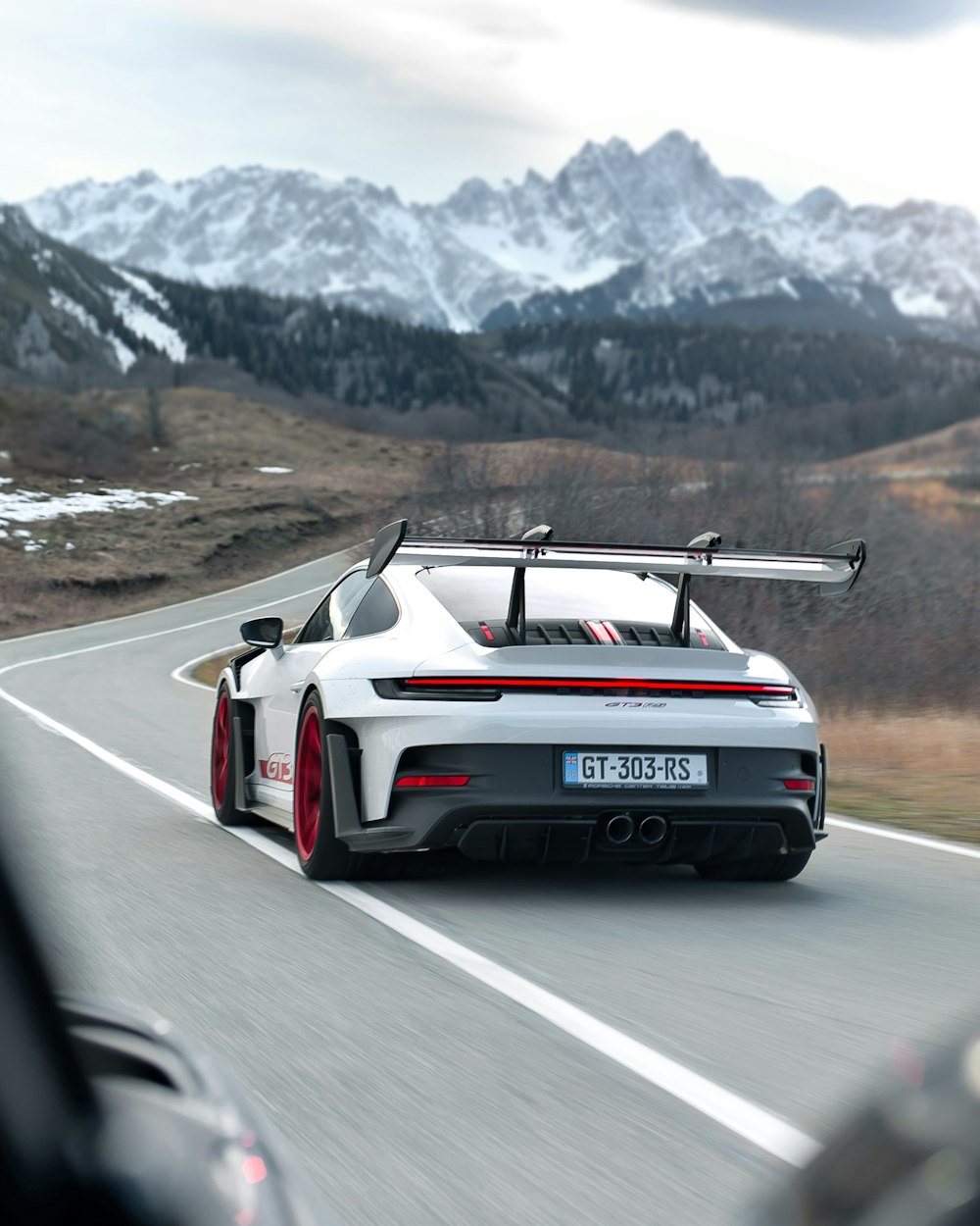 um carro esportivo branco dirigindo por uma estrada de montanha