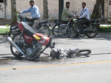 Two appraisers discussing a vehicle's condition beside a motorcycle with visible damage.