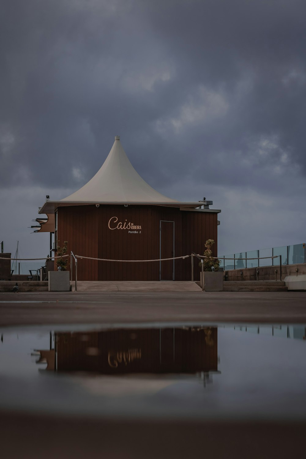 a brown building with a white roof and water