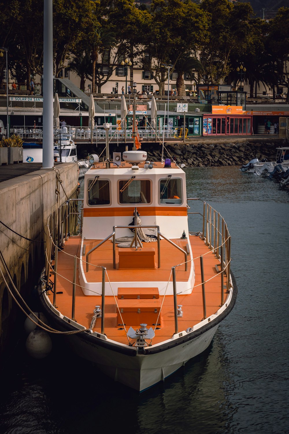 an orange and white boat docked at a dock