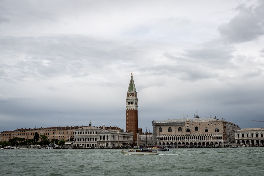 una grande torre dell'orologio che sovrasta una città accanto a uno specchio d'acqua